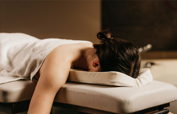 woman lying in a prone position, while her face is supported by a face cushion