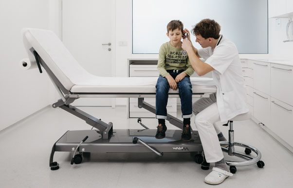 doctor examines a boy sitting on an examination table